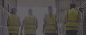four workers in safety vests walking in a warehouse