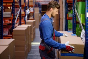 male employee in a blue shirt lifting a box in the factory