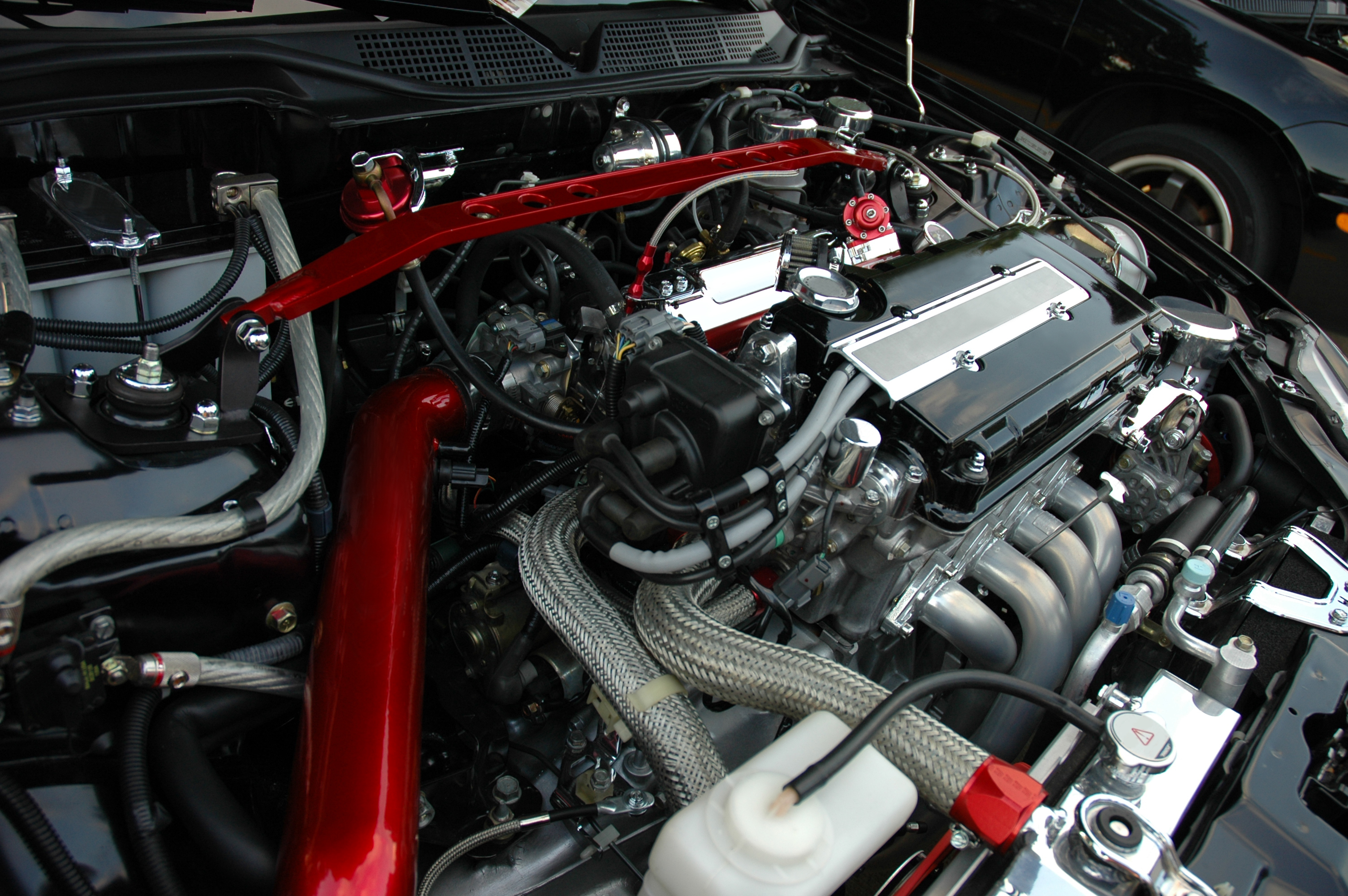 A modified motor running under the hood of a sport compact car.